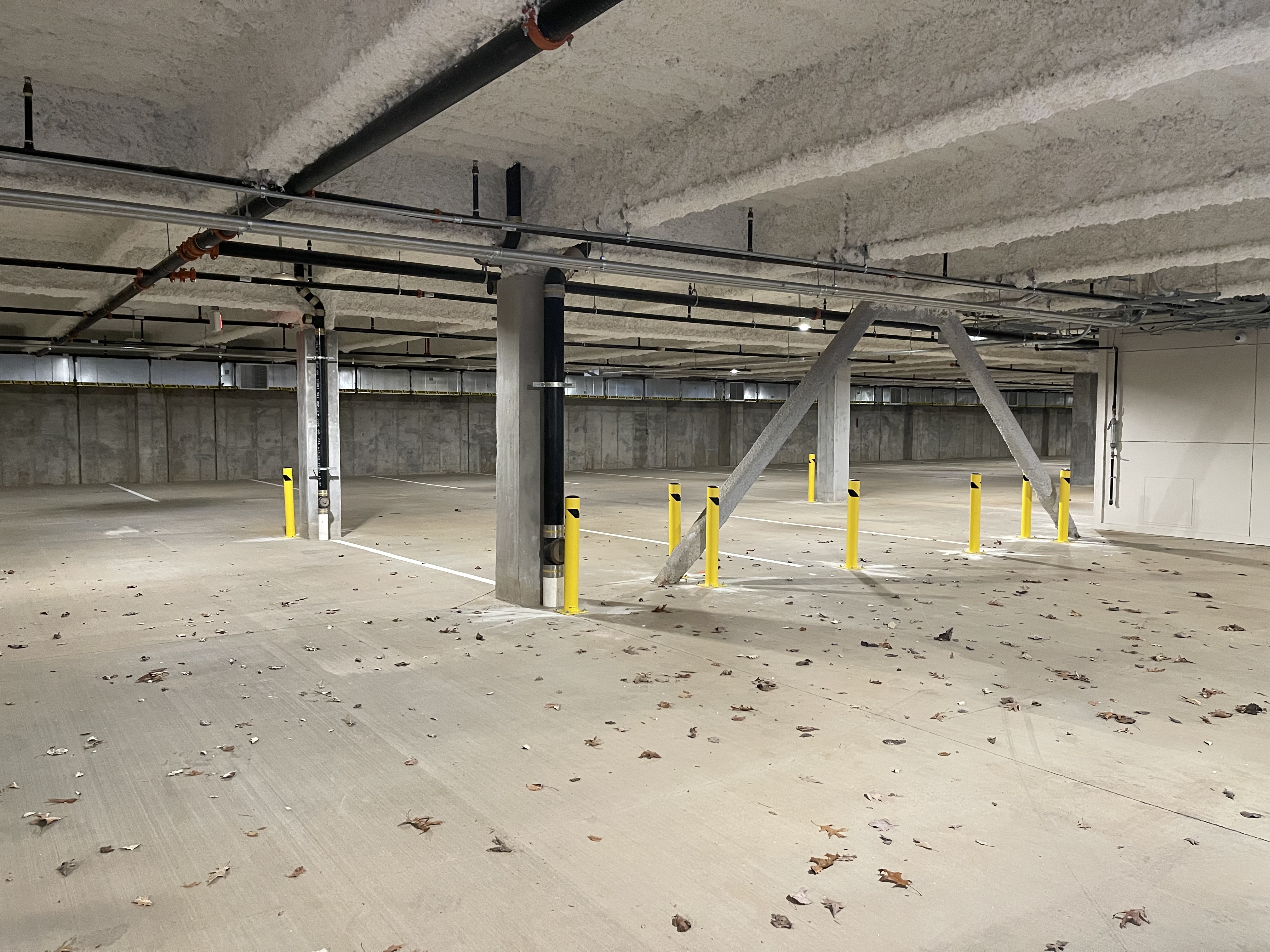 Parking garage after bollard installation with yellow safety bollards protecting columns