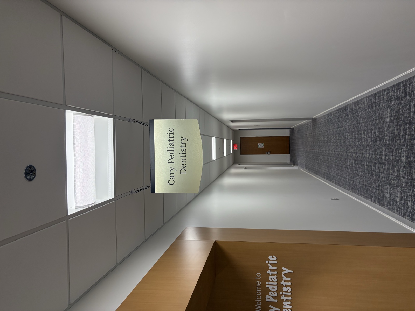 Medical office corridor with hanging directional wayfinding sign installed overhead
