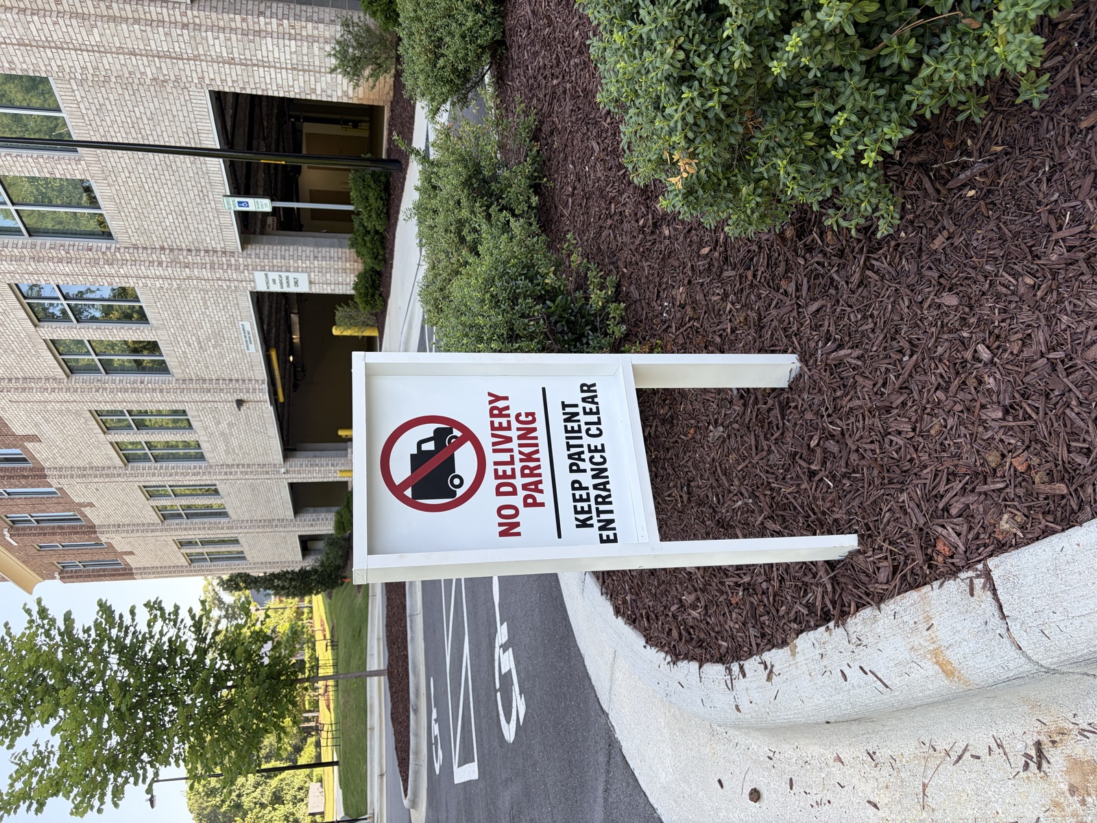 Custom wood-framed exterior No Delivery Parking sign at the medical building entrance